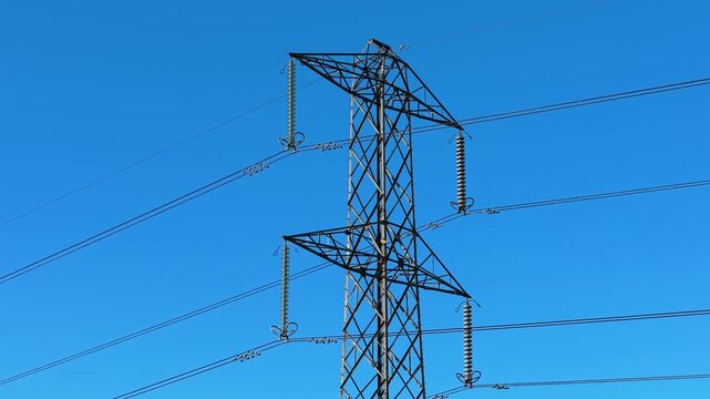 Massive transmission pylon carrying multiple electric lines. Network of towers carrying high voltage electricity. Tall steel construction supporting suspended conductors