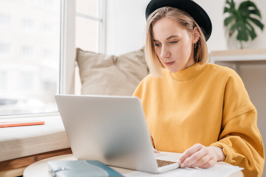 Blonde young woman working on laptop, close up