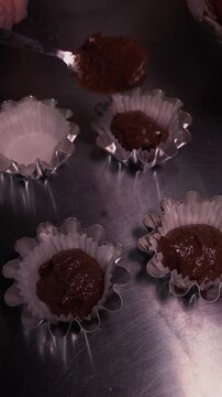 A female baker prepares cupcakes using a pastry bag. Vertical video about homemade pastries, cooking and confectionery.