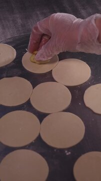 A woman cooks dumplings with meat filling. Vertical video.
