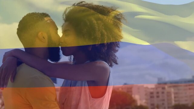 Animation of waving colombia flag against african american couple kissing outdoors