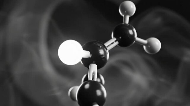 Black and white close-up of a molecular structure model with glowing sphere against smoky background