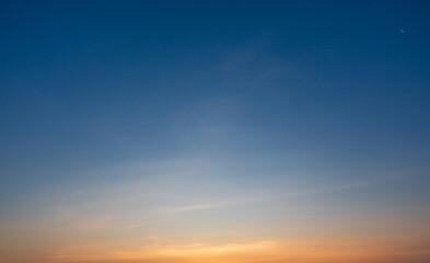 Fototapeta premium Clear blue sky at sunrise with subtle clouds and warm light forming a peaceful mood.