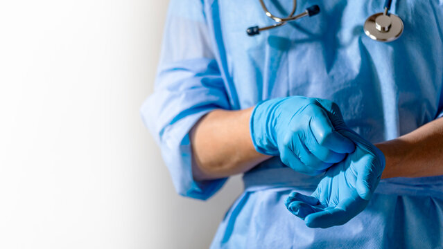 Healthcare professional putting on blue medical gloves on white background with copy space