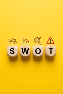 Wooden blocks spelling out swot analysis with related icons placed above on yellow background