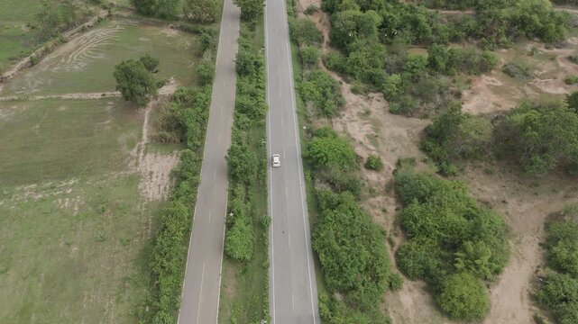 Aerial drone footage of car driving on rural road through countryside landscape, travel journey, transportation and scenic nature environment