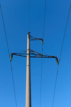 Energy Industry: Overhead medium-voltage power line with concrete poles in front of a cloudless blue sky