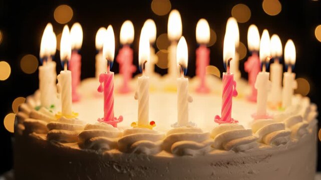Birthday cake with many lit candles on a dark background with bokeh lights