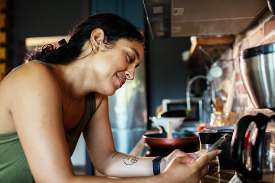 Woman using smartphone in home kitchen