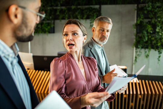 Business colleagues debating paperwork in modern office lobby