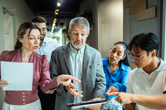 Concerned coworkers reviewing paperwork in office hallway