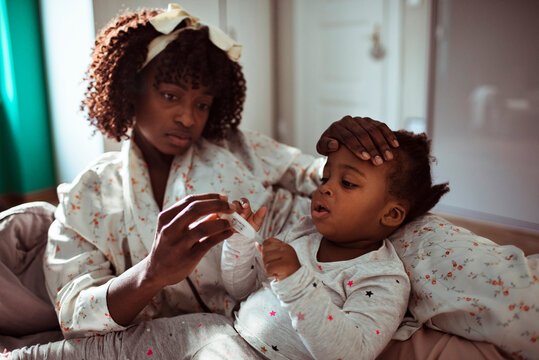 Mother checking sick toddler's temperature at home