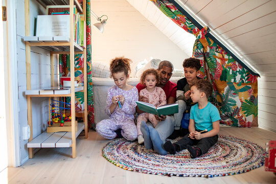 Parent reading a story to children in cozy attic playroom at home