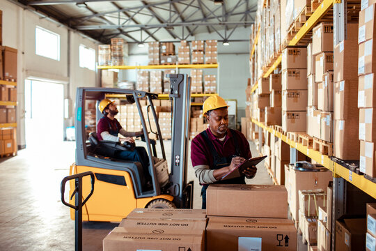 Workers checking inventory with forklift in warehouse
