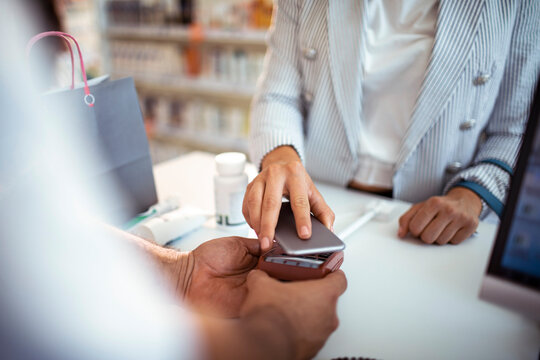 Customer using smartphone for contactless payment at pharmacy checkout