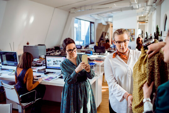 Women fashion designers collaborating on dress in modern studio