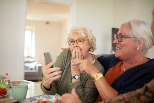 Senior friends react to smartphone message at home