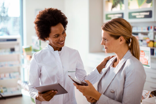 Pharmacist advising customer with smartphone in pharmacy