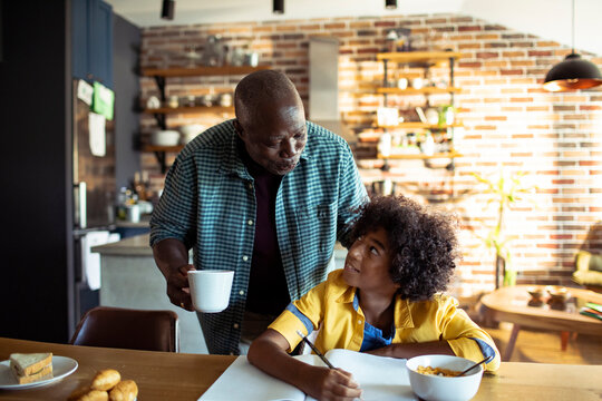 Grandfather helping grandson with homework at kitchen table