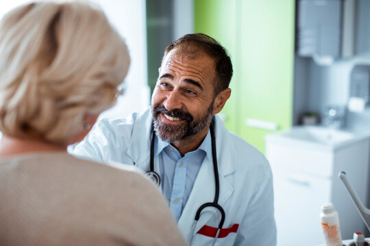 Smiling male doctor reassuring senior patient in clinic