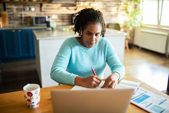 Focused woman working and budgeting at home kitchen