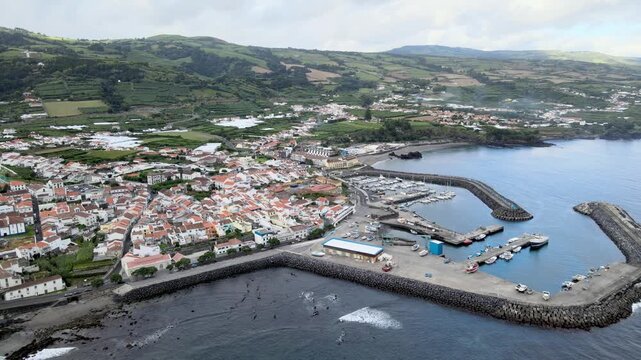 Aerial drone view of Vila Franca do Campo on S&atilde;o Miguel Island. From high altitude, the coastal town is visible with red-roof houses, agricultural fields and green landscape. The harbor and marina ext