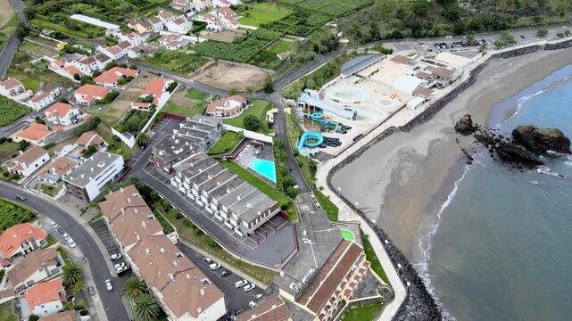 Aerial drone view of Vila Franca do Campo on S&atilde;o Miguel Island. From high altitude, the coastal town is visible with red-roof houses, agricultural fields and green landscape. The harbor and marina ext
