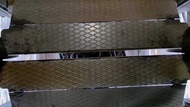 detailed view flexible gangway connection linking two passenger train cars, showing movement and vibration metal plates and bellows as train travels along tracks. top view. close up.
