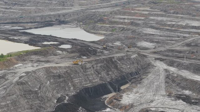 Aerial view of a vast coal mine and blackened excavation pits filled with coal