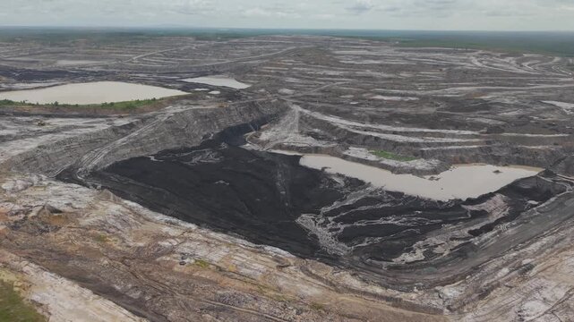 Aerial view of a vast coal mine and blackened excavation pits filled with coal