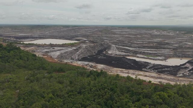 Aerial view of a vast coal mine and blackened excavation pits filled with coal