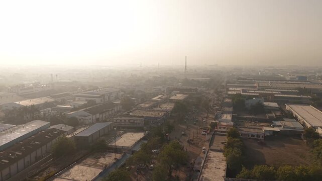 The sun, illuminates rows of large-span industrial warehouses, factories, and manufacturing plants.