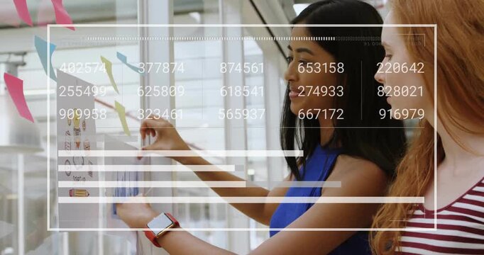 Two colleagues picking printed chart from stack and aligning planning graph on transparent wall