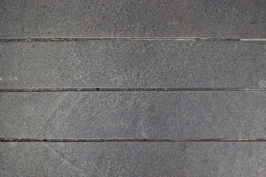 Texture of gray natural stone flooring with neat cement borders for building exterior areas.