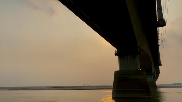 Beautiful sunset over Jamuna river and the Jamuna Bridge. Colorful reflections in the water. Sunset on the river bridge. Railway bridge at beautiful sunset. Sunset through a bridge.
