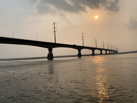 Beautiful sunset over Jamuna river and the Jamuna Bridge. Colorful reflections in the water. Sunset on the river bridge. Railway bridge at beautiful sunset. Sunset through a bridge.