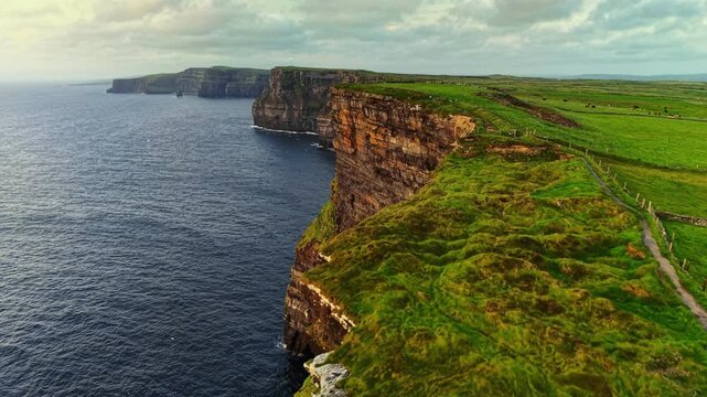Aerial view of the Cliffs of Moher, Ireland. Drone flies along Cliffs of Moher landscape in Ireland with emerald green fields meet the crashing waves of the Atlantic Ocean