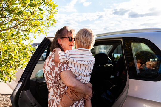 Middle aged Australian woman helping grandchild get into car seat to go to preschool