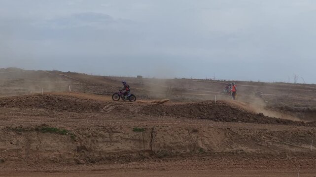 Aerial drone footage of motocross cross country race, dirt bikes speeding on rugged track, riders competing in off-road extreme motorsport event, dynamic action and dust clouds