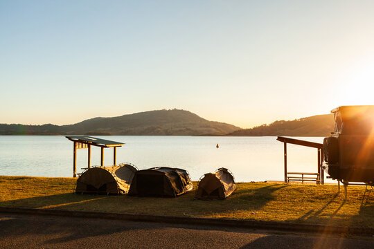 Three swags set up by picnic shelters at lake in sunset light