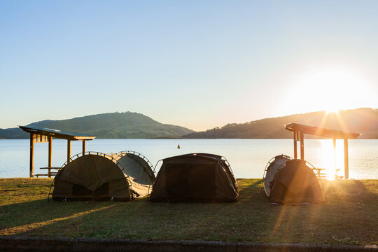Three swags set up by picnic shelters at lake in sunset light