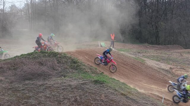 Aerial drone footage of motocross cross country race, dirt bikes speeding on rugged track, riders competing in off-road extreme motorsport event, dynamic action and dust clouds