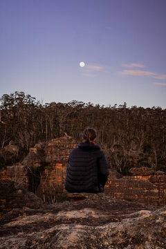 Man watching moon sitting on mountain cliff