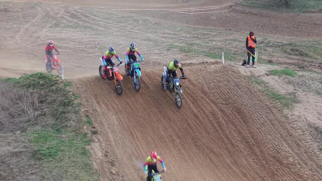 Aerial drone footage of motocross cross country race, dirt bikes speeding on rugged track, riders competing in off-road extreme motorsport event, dynamic action and dust clouds