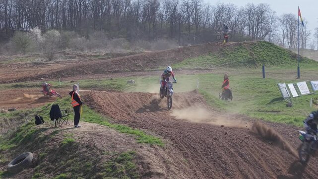 Aerial drone footage of motocross cross country race, dirt bikes speeding on rugged track, riders competing in off-road extreme motorsport event, dynamic action and dust clouds