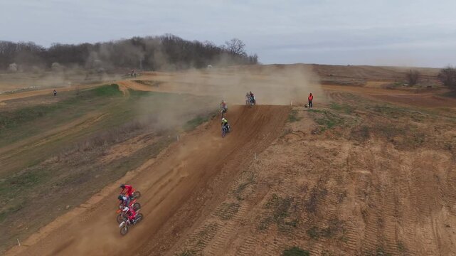 Aerial drone footage of motocross cross country race, dirt bikes speeding on rugged track, riders competing in off-road extreme motorsport event, dynamic action and dust clouds