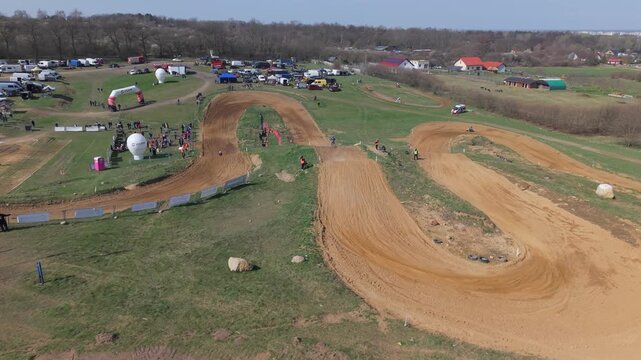 Aerial drone footage of motocross cross country race, dirt bikes speeding on rugged track, riders competing in off-road extreme motorsport event, dynamic action and dust clouds