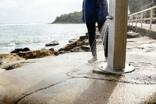 Close up of a persons bare feet rinsed under an outdoor shower