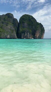 Maya Bay turquoise water and limestone cliffs vertical video, iconic beach destination in Thailand travel scene.