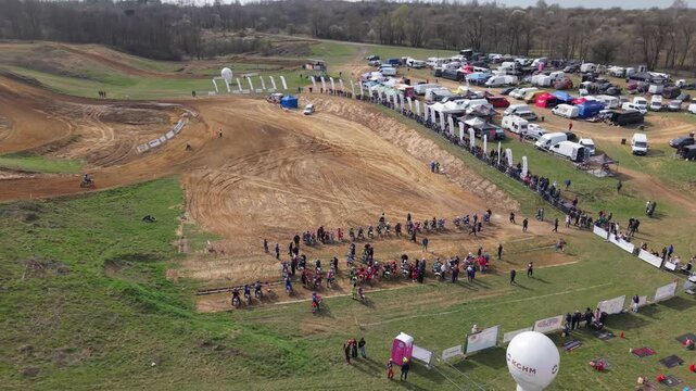 Aerial drone footage of motocross cross country race, dirt bikes speeding on rugged track, riders competing in off-road extreme motorsport event, dynamic action and dust clouds